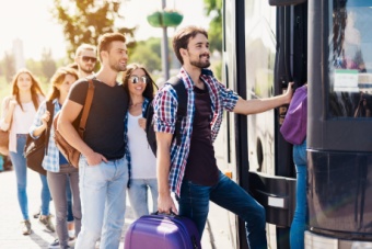 A group of passengers wait to board a bus