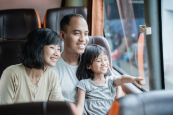 A smiling family looks out the window of a charter bus