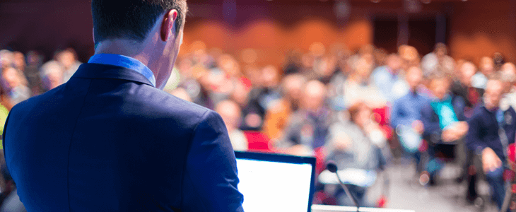 view from behind of a speaker talking to a large group