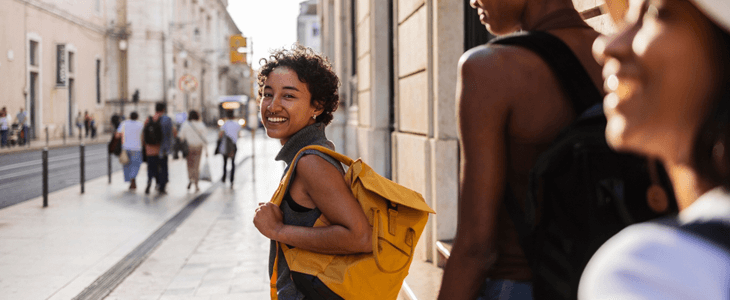 a woman wearing a backpack smiles at the camera