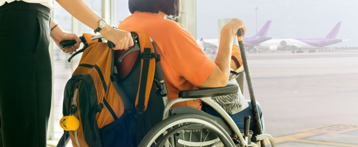 a wheelchair user looks out the window at an airport