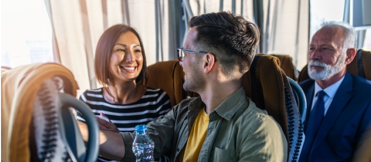 Two employees sit next to each other on a charter bus
