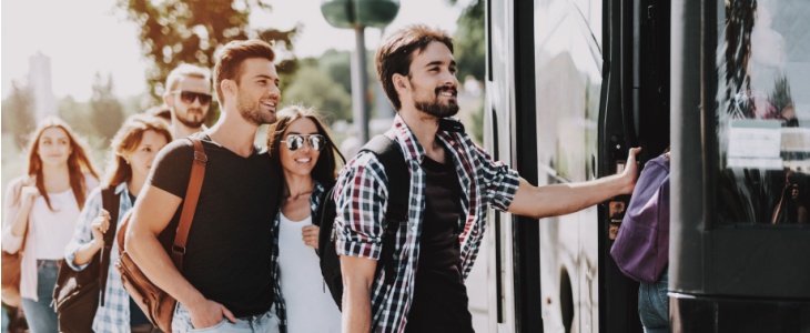 a group of employees line up to board a charter bus