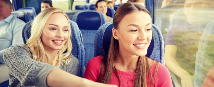 Two young athletes look out the window of a charter bus