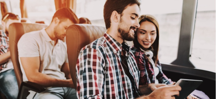Two people on a charter bus looking at a tablet