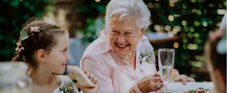 A grandmother and granddaughter sit next to each other at a wedding reception